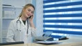 Pretty nurse using tablet and phone at hospital reception desk Royalty Free Stock Photo