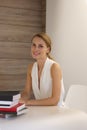 Pretty office worker sitting behind the desk in clear bright room Royalty Free Stock Photo