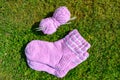 Pretty pair of pink wool socks. Cotton yarn ball and set of needles. A couple of rose baby footwear