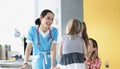 Pretty pediatrician chatting with cute patient child girl on appointment in clinic