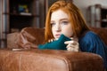 Pretty pensive redhead girl lying on sofa and thinking