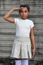 Pretty Philippina Child Saluting Wearing Skirt Near Wall