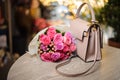 Pretty pink flowers near the stylish handbag on the table Royalty Free Stock Photo