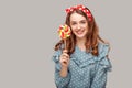 Pretty pinup girl ruffle blouse holding sweet spiral candy looking at camera, smiling with delicious confectionery