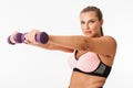 Pretty plump girl in sporty top doing exercises with dumbbells while dreamily looking in camera over white background Royalty Free Stock Photo