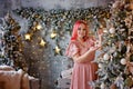 A pretty plump woman with pink hair is decorating a Christmas tree with balloons Royalty Free Stock Photo