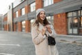 Pretty positive girl with cute smile outdoors. Fashion model of a young woman in fashionable coat in a knitted stylish hat with a Royalty Free Stock Photo