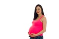 Pretty pregnant girl with dark hair touching her big belly and looking at the camera isolated on white background Royalty Free Stock Photo