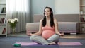 Pretty pregnant meditating while listening to music, thinking about baby