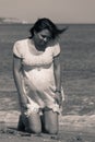 Pretty pregnant woman kneeling down on the beach Royalty Free Stock Photo