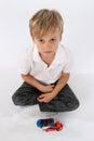 Pretty preschool boy sitting with a set of toys and wondering, what now?