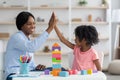 Pretty preschool teacher exercising with happy little girl at kindergarten Royalty Free Stock Photo