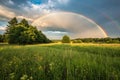 Pretty rainbow in a field with trees Royalty Free Stock Photo
