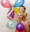 Pretty real family with color balloons on white background, blond woman with little boy at birthday party bright smiling Royalty Free Stock Photo