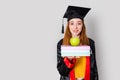 A pretty red haired female student, holding her study books and celebrating her graduation with success. Royalty Free Stock Photo