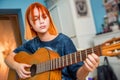 Pretty red-haired teenage girl plays guitar in her room Royalty Free Stock Photo