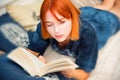 Pretty red-haired teenage girl reads book in her room Royalty Free Stock Photo