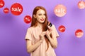 Pretty red-haired woman with present, credit cards looking at the camera Royalty Free Stock Photo