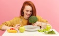 Pretty redhead caucasian woman sitting at table with healthy food and broccoli