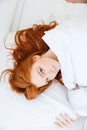 Pretty redhead woman with long hair lying in bed