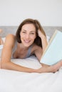 Pretty relaxed woman reading book in bed