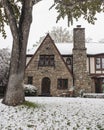 Pretty rock house with arched door and Tudor style leaded glass diamond panel windows during snowfall