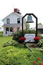 Pretty scene of landscaped yards and bell in front of Sodus Point Lighthouse, Sodus Point NY, summer, 2022