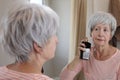 A pretty senior woman in her sixties is using some delicious perfume Royalty Free Stock Photo