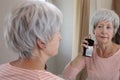 A pretty senior woman in her sixties is using some delicious perfume Royalty Free Stock Photo