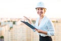 Pretty young forewoman in helmet stand on the roof with tablet i