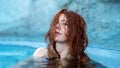 Pretty sexy, seductive, redhead woman portrait relaxes in turquoise, blue thermal bath hot water pool in hot steam Royalty Free Stock Photo