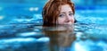 Pretty sexy, seductive, sensual redhead woman portrait relaxes swimming in turquoise, blue thermal bath hot water pool, happy Royalty Free Stock Photo