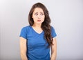 Pretty shocked woman with brunette hair and wide opened eyes in casual t-shirt dress looks scared. Studio shot