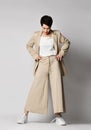 Pretty short haired brunette woman in beige business smart casual suit and skeakers standing and posing