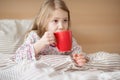 Pretty sick little child girl laying in bed drink tea