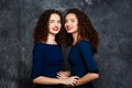 Pretty sisters twins smiling looking at camera over grey background.