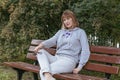 Pretty, slender middle-aged woman, 50 years old, blonde sitting on a bench