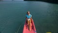 Pretty slim woman in elegant swimsuit lies in pink plastic kayak drifting on azure ocean at exotic resort upper view.