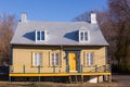 Pretty small yellow wooden ancestral neoclassical house with metal sheet roof in Saint-Jean