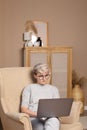 Pretty smart woman about 30s in casual clothes sitting in a chair with laptop