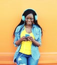 Pretty smiling african woman with headphones listens to music over orange Royalty Free Stock Photo