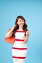 Pretty smiling Asian woman with shopping bags showing credit card in hand studio shot isolated on blue background Royalty Free Stock Photo