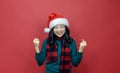 Pretty smiling asian woman in warm christmas sweater and santa hat is having excitement on red background for season celebration Royalty Free Stock Photo