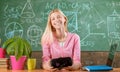 Pretty smiling blonde girl sitting at desk in the classroom in school and having a lesson. Happy teen pupil getting new