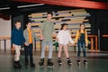 Pretty smiling children with handsome trainer standing in roller rink and