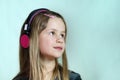 Pretty smiling cild girl listening to music in big pink earphones Royalty Free Stock Photo