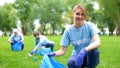 Pretty smiling female collecting forest garbage, looking at camera, volunteering