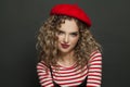 Pretty smiling french woman fashion model in red beret on black background portrait