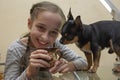 Pretty smiling girl. Her chihuahua dog poses near. Girl and chihuahua at the table Royalty Free Stock Photo