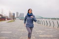 Pretty girl jogging on the river bank. Cloudy rain day Royalty Free Stock Photo